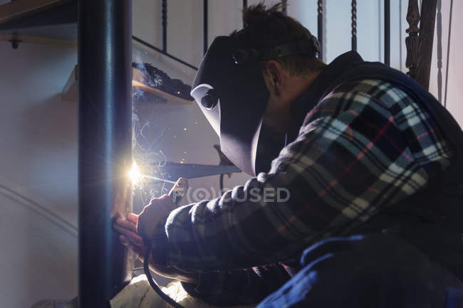 Homem trabalhando em escada em espiral com tocha elétrica — Fotografia de Stock