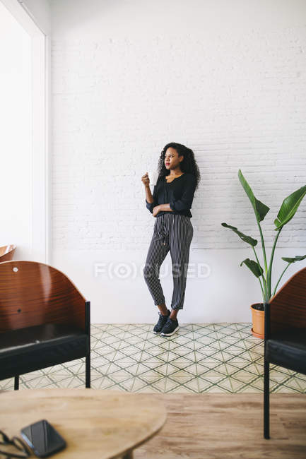 Junge Geschäftsfrau steht in modernem Büro vor weißer Wand — Stockfoto