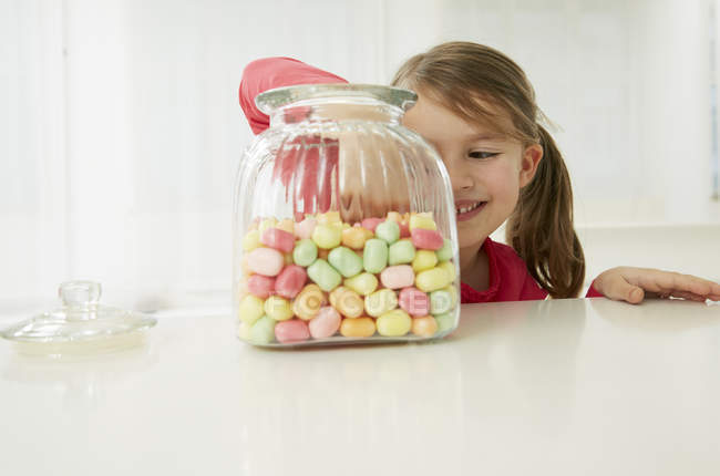 Girl with candy jar choosing one — Stock Photo