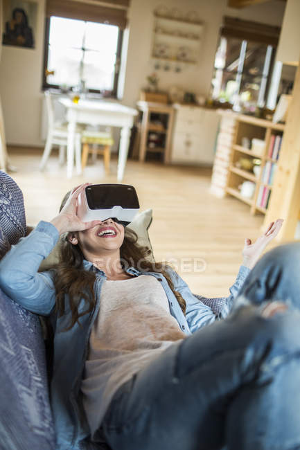 Молода жінка вдома використовує окуляри віртуальної реальності — стокове фото