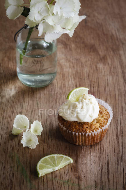 Cupcake de limão com cobertura de queijo creme em madeira com flores — Fotografia de Stock