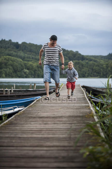 Allemagne, Rhénanie-Palatinat, Laacher See, père courant avec son fils sur une jetée — Photo de stock