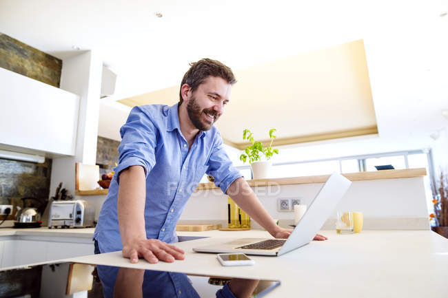 Mann arbeitet in Küche mit Laptop — Stockfoto