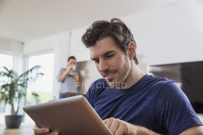 Hombre en casa usando tableta digital - foto de stock