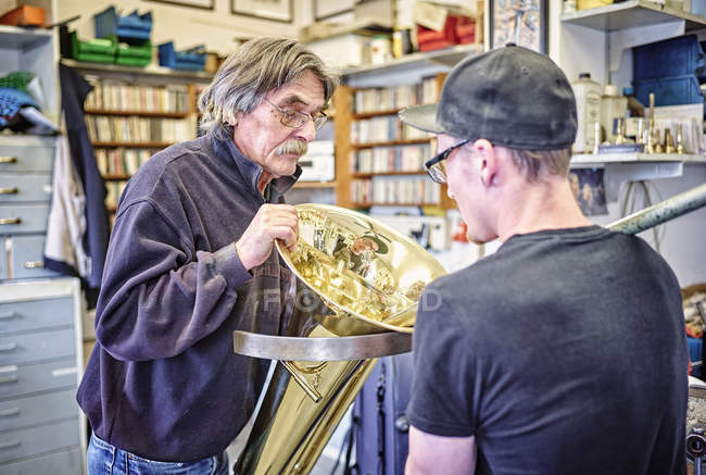 Due costruttori di strumenti che riparano gli strumenti in ottone in officina — Foto stock