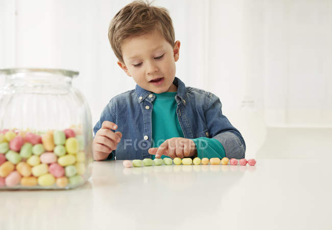 Ragazzo con barattolo di caramelle, contando caramelle — Foto stock