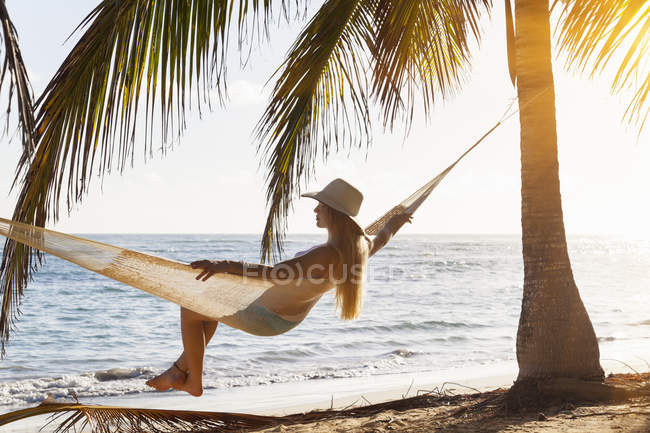 Dominicana Rebublic, Giovane donna in amaca guardando fuori sulla spiaggia tropicale — Foto stock