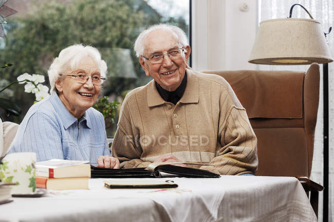 Seniorenpaar schaut sich zu Hause alte Fotos an — Stockfoto
