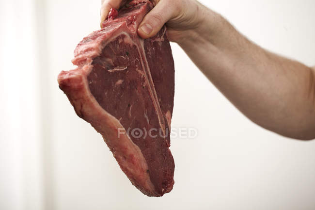 Close-up of male hand holding beef steak — Stock Photo