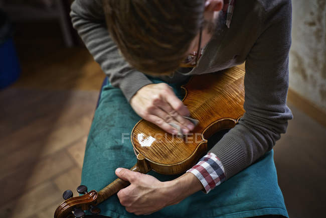 Violin maker polishing repaired violin — Stock Photo