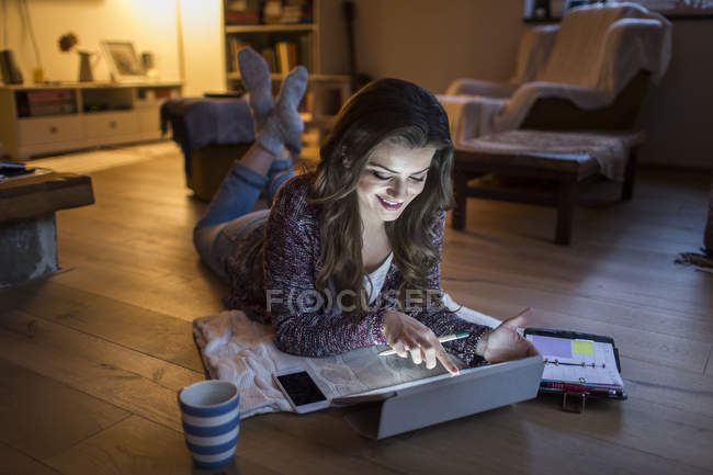 Mujer joven en casa trabajando con tableta digital - foto de stock