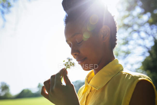 Retrato de sorrir jovem mulher cheirando flores — Fotografia de Stock