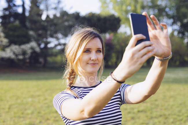 Retrato de mulher loira relaxada tirando selfie com smartphone — Fotografia de Stock
