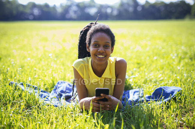 Портрет молодой женщины со смартфоном, отдыхающей на лугу — стоковое фото