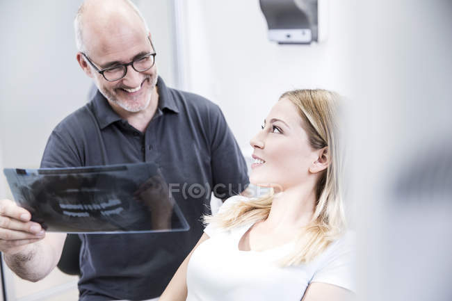 Dentista che mostra l'immagine a raggi X al paziente — Foto stock