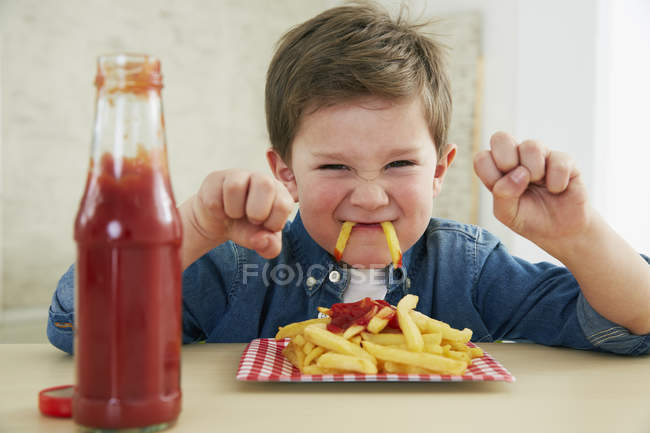 Junge isst Pommes mit Ketchup — Stockfoto