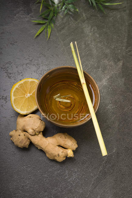 Té de limón de jengibre en un tazón de té con hierba de limón fresca y jengibre - foto de stock