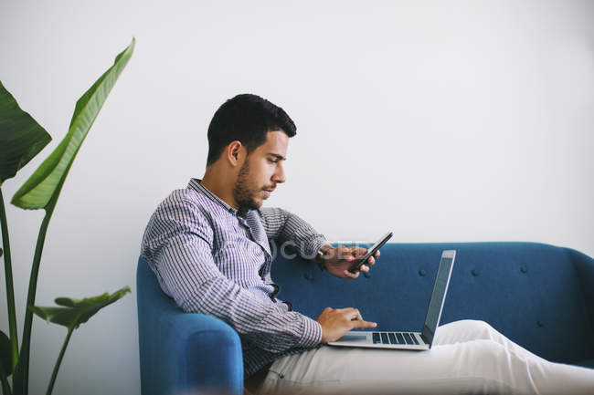 Geschäftsmann sitzt mit Laptop auf Sofa im Büro — Stockfoto