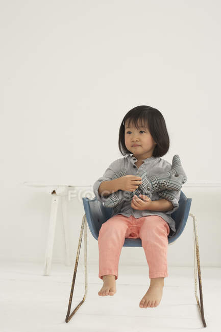 Little Asian Girl With Soft Toy Sitting On A Chair Stock Photo Little Asian Girl With Soft Toy Sitting On A Chair Stock Photo