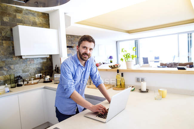 Mann arbeitet in Küche mit Laptop — Stockfoto