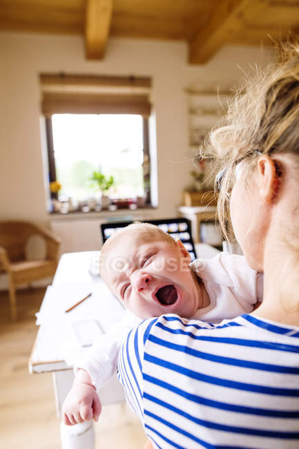 Mother at home holding crying baby — Stock Photo