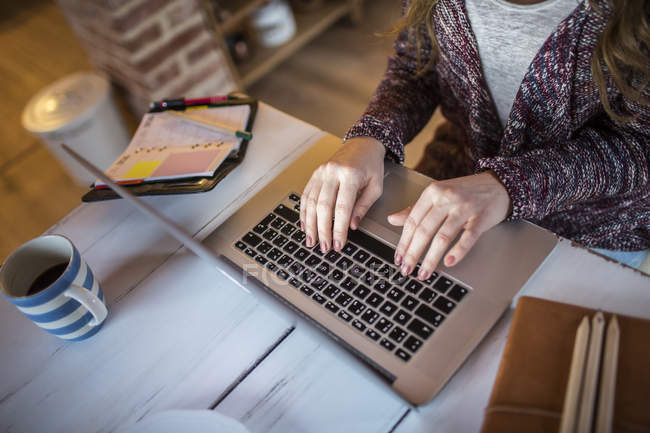 Mujer joven en casa trabajando con portátil - foto de stock