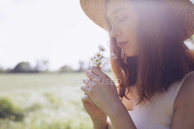 Young woman with daisies at backlight — Stock Photo