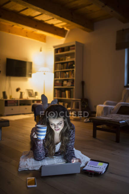 Mujer joven en casa trabajando con tableta digital - foto de stock