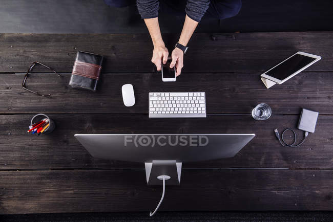 Hombre trabajando en el escritorio con ordenador y varios aparatos digitales - foto de stock