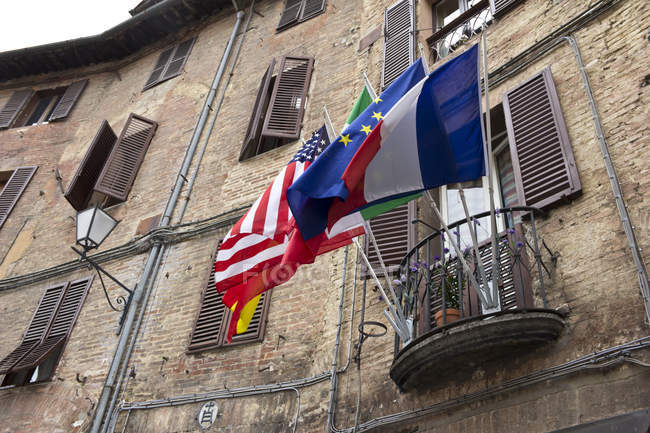 Italia, Toscana, Siena, Bandiere diverse su un balcone di vecchio edificio — Foto stock