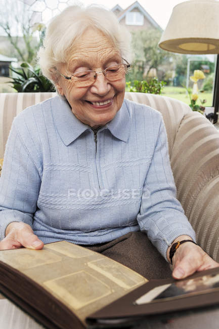 Senior woman watching old photographs at home — Stock Photo