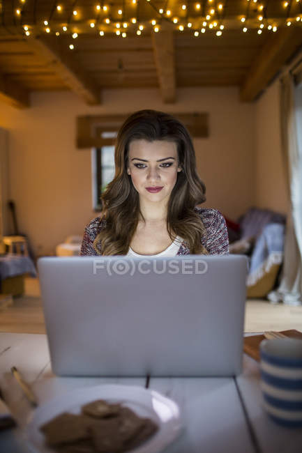 Mujer joven en casa trabajando con portátil - foto de stock