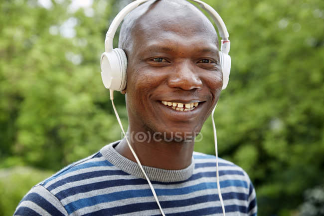 Retrato del hombre africano sonriente con auriculares - foto de stock