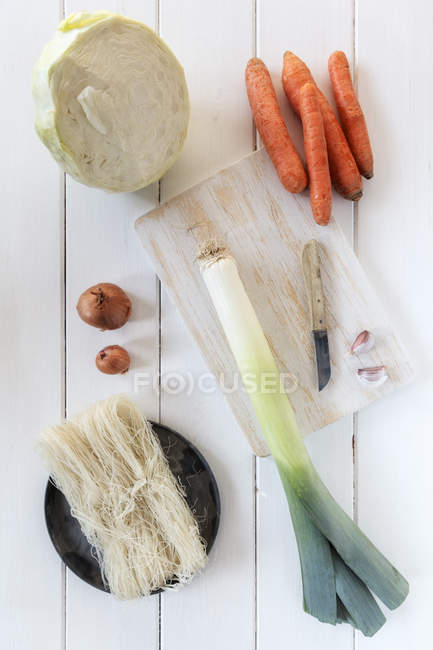 Ingredients for wok dish on white wood with chopping board and knife — Stock Photo