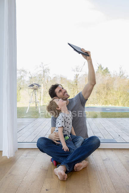 Father And Son Sitting On Floor Using Digital Tablet Toothy