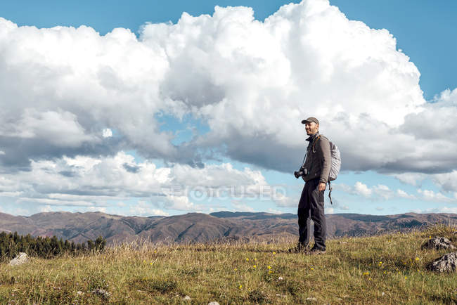 Peru, Cusco, homem de caminhada com câmera e mochila em pé na montanha — Fotografia de Stock