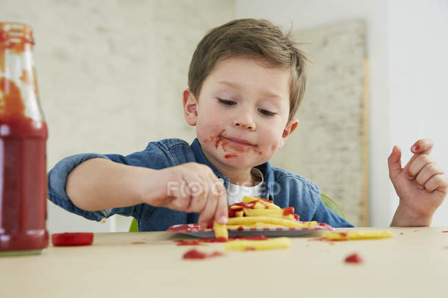 Junge isst Pommes mit Ketchup — Stockfoto