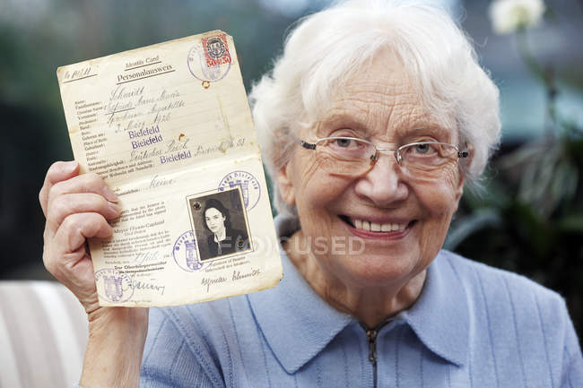 Mujer mayor mostrando su antiguo pasaporte temporal - foto de stock