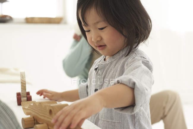 Petite fille asiatique jouant avec son jouet en bois — Photo de stock