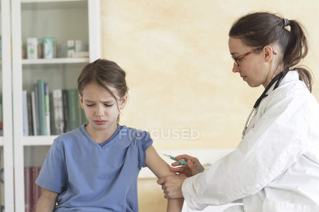 Педиатр готовит медицинскую инъекцию грустной девушке в клинике — стоковое фото