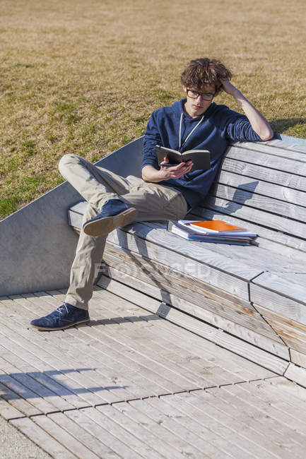 Germania, Baden-Wurttemberg, Ragazzo adolescente seduto sulla panchina, imparando — Foto stock