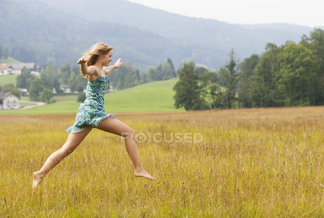 Austria, Salzkammergut, Mondsee, giovane donna che salta in un prato — Foto stock