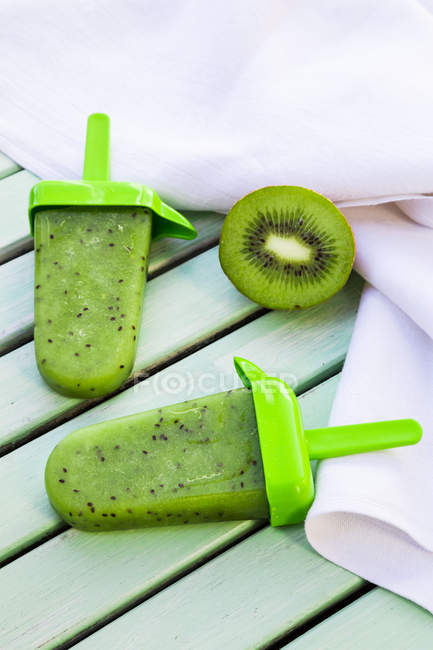 Two Kiwi Ice Cream Lollies And Half Of Kiwi On White Wood Frozen Green Stock Photo Two Kiwi Ice Cream Lollies And Half Of Kiwi On White Wood Frozen Green Stock Photo