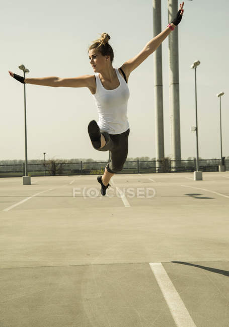 Молодая женщина прыгает в воздухе на уровне парковки — стоковое фото