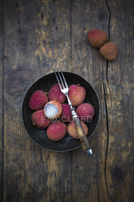 Миска свіжої litchis з виделкою на темного дерева — стокове фото
