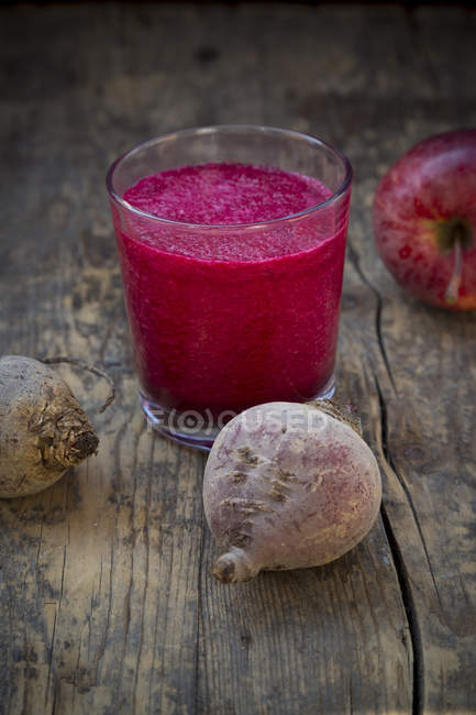 Glass of apple beetroot smoothie with ingredients on dark wooden table — Stock Photo