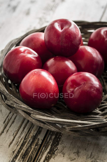 Bowl of red plums on shabby wooden table — Stock Photo