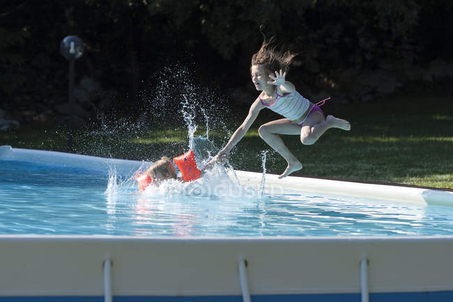 Children Jumping Into Swimming Pool In Summer Outdoors — Swimwear