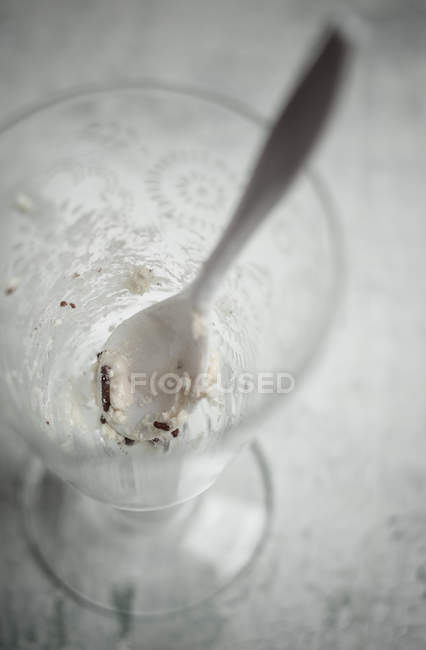 Vidrio con restos de helado de vainilla con gránulos de chocolate y una cuchara - foto de stock