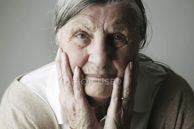 Retrato de mujer mayor con la cabeza en las manos - foto de stock